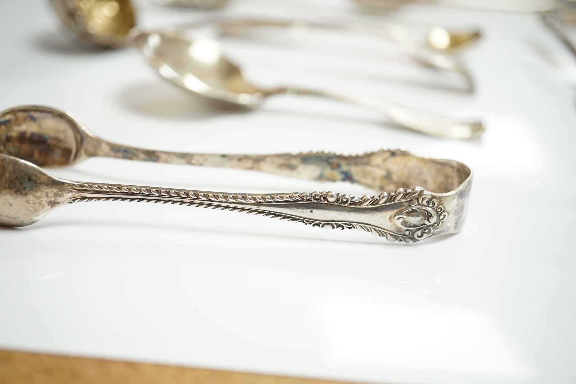 Ten assorted items of silver flatware including a mid 18th century mote spoon by Elizabeth Jackson?, 14.8cm, a George IV caddy spoons, two pairs of sugar tongs, four condiment spoons, a butter knife and sauce ladle, 6.8o